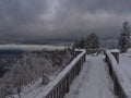 Winter landscape with snow-covered observation deck and bench on Schliffkopf peak, Germany with view over Black Forest. Royalty Free Stock Photo