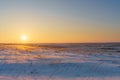 Winter landscape with snow covered plain, blue sky and orange su Royalty Free Stock Photo