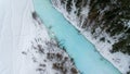 Winter landscape with snow forest and the blue river captured from above with a drone.