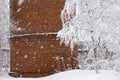 Winter landscape. Snowfall on the background of a part of a brick wall and trees covered with snow Royalty Free Stock Photo