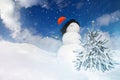 Winter landscape with a snowman and a snow-covered Christmas tree on a blue sky background Royalty Free Stock Photo