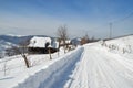 Winter landscape with snowy country road and wooden houses. Royalty Free Stock Photo
