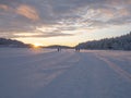 Winter landscape, sunset over a snowy forest and a frozen lake. Skiers and people walking in the background. Royalty Free Stock Photo