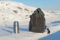 Winter landscape,thermos, and backpack are on the snow .