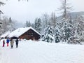 Snowy winter in a tourist village in the mountains. Wooden building and people with ski poles. Zakopane, Tatra mountains, Poland
