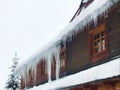 Long icicles on a traditional wooden building. House in mountain town in winter. Windows, snow, ice. Zakopane, Poland, Tatra mount