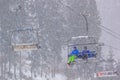 Winter landscape - view of the chairlift lift with skiers in the winter mountain forest during a snowfall, Bukovel ski resort, Car