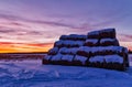 Winter landscape with view of snow-covered straw bales in field at sunset Royalty Free Stock Photo