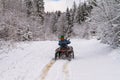 Winter landscape - view of the snowy road with a quad bike in the winter mountain forest Royalty Free Stock Photo