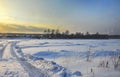 Winter landscape. Village on the bank of a snow-covered river. Beautiful sunset and big snowdrifts. Frozen river road. Royalty Free Stock Photo