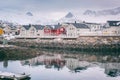 Winter landscape with white and red houses, reflection in the water and snowy mountain peaks, Kabelvag, Lofoten Islands, Norway Royalty Free Stock Photo