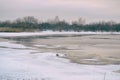 Winter freezing sea with ice floes. A small island with dark gloomy forest in the distance. Northern cloudy day, tranquility of Royalty Free Stock Photo