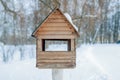 Winter landscape. Wooden birdhouse in snow-covered garden. Blurry photography with a shallow depth of field. Cold winter day