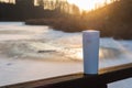 Winter landscape with a wooden bridge over a lake with reeds, and a white thermos flask Royalty Free Stock Photo