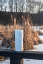 Winter landscape with a wooden bridge over a lake with reeds, and a white thermos flask Royalty Free Stock Photo