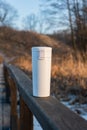 Winter landscape with a wooden bridge over a lake with reeds, and a white thermos flask Royalty Free Stock Photo