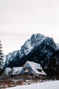 Winter landscape of a wooden house on a background of snow-covered forest and mountains. Place for text or advertising Royalty Free Stock Photo