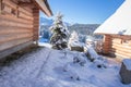 Winter landscape with wooden house and snowy Christmas trees in mountain valley. Skiing resort in mountains. Wintry nature