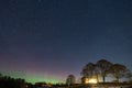 Winter landscape with wooden house under a beautiful starry sky and Northern Lights Royalty Free Stock Photo