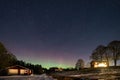 Winter landscape with wooden house under a beautiful starry sky and Northern Lights Royalty Free Stock Photo