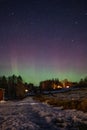 Winter landscape with wooden house under a beautiful starry sky and Northern Lights Royalty Free Stock Photo