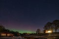 Winter landscape with wooden house under a beautiful starry sky and Northern Lights Royalty Free Stock Photo