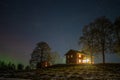 Winter landscape with wooden house under a beautiful starry sky and Northern Lights Royalty Free Stock Photo