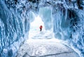 Winter Landscape, Frozen ice cave with young photographer standing alone. Traveling in winter Royalty Free Stock Photo
