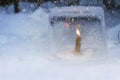Winter lantern made of ice, burning candle inside, in snowfall Royalty Free Stock Photo