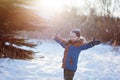 Winter little child playing throws up snow outdoors during snowfall. Active outoors leisure with children in winter on cold snowy