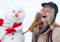 Winter love concept. Happy girl plaing with a snowman on a snowy winter walk. Making snowman and winter fun. Crazy