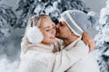 Winter love story with couple weared fur headphones, hats, white sweaters. Happy young couple hugs and kiss near