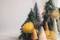 Winter magic forest, festive modern decor. Christmas little trees and golden lights bokeh on white background. Copy space. Royalty Free Stock Photo
