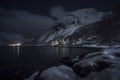 Winter Magic: A Quaint Village Nestled Along a Snow-Covered Fjord Shoreline, Illuminated by Night Lights, ai generative