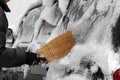 Winter. A man with a broom cleans car from snow on the street after big snowstorm in the city, all cars under snow, icy roads, sno Royalty Free Stock Photo