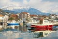 Winter Mediterranean landscape. Fishing boats in harbor on background of snowy mountains. Montenegro, Tivat city Royalty Free Stock Photo