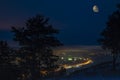 Winter moonscape of night city lights from a high mountain with coniferous trees Royalty Free Stock Photo