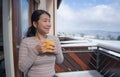 Winter morning coffee - young happy and attractive Asian Chinese woman at hotel or home balcony in the snow drinking coffee Royalty Free Stock Photo