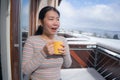 Winter morning coffee - young happy and attractive Asian Chinese woman at hotel or home balcony in the snow drinking coffee Royalty Free Stock Photo