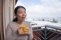 Winter morning coffee - young happy and attractive Asian Chinese woman at hotel or home balcony in the snow drinking coffee Royalty Free Stock Photo