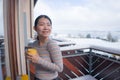 Winter morning coffee - young happy and attractive Asian Japanese woman at hotel or home balcony in the snow drinking coffee Royalty Free Stock Photo