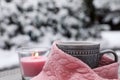 Winter morning. Cup with hot drink wrapped in pink sweater and burning candle outdoors, closeup. Space for text Royalty Free Stock Photo