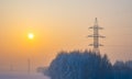 Winter morning landscape of snow covered nature, trees and large poles of high voltage power transmission lines Royalty Free Stock Photo