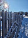 Winter morning in the village. A snow-covered wooden fence. Sunny morning. The photo can be used for any purpose