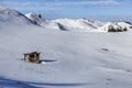 Winter mountain background with small wooden alpine cottage, on a snow field Royalty Free Stock Photo