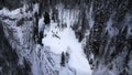 Winter mountain cliff covered by snow, ice, and fur trees. Clip. Stunning frozen winter nature, aerial view of tourists Royalty Free Stock Photo