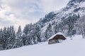 Winter mountain landscape in the Alps. Old traditional stable cowshed for cows and horses. Farm building built of stones and wood.