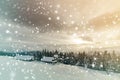 Winter mountain landscape. Old wooden houses on snowy clearing on background of mountain ridge, spruce forest and cloudy sky. Royalty Free Stock Photo