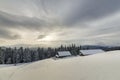 Winter mountain landscape. Old wooden houses on snowy clearing on background of mountain ridge, spruce forest and cloudy sky. Royalty Free Stock Photo