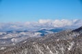 Winter mountain landscape. Snow-capped mountains overgrown with coniferous taiga against the background of clouds and Royalty Free Stock Photo